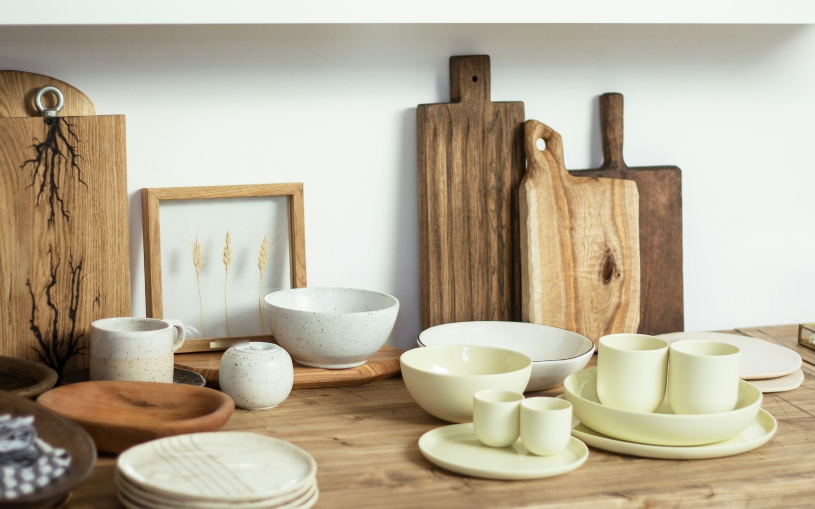 Vaisselle en céramique, planches à découper en bois et cadre d'épis de blé sur une table en bois