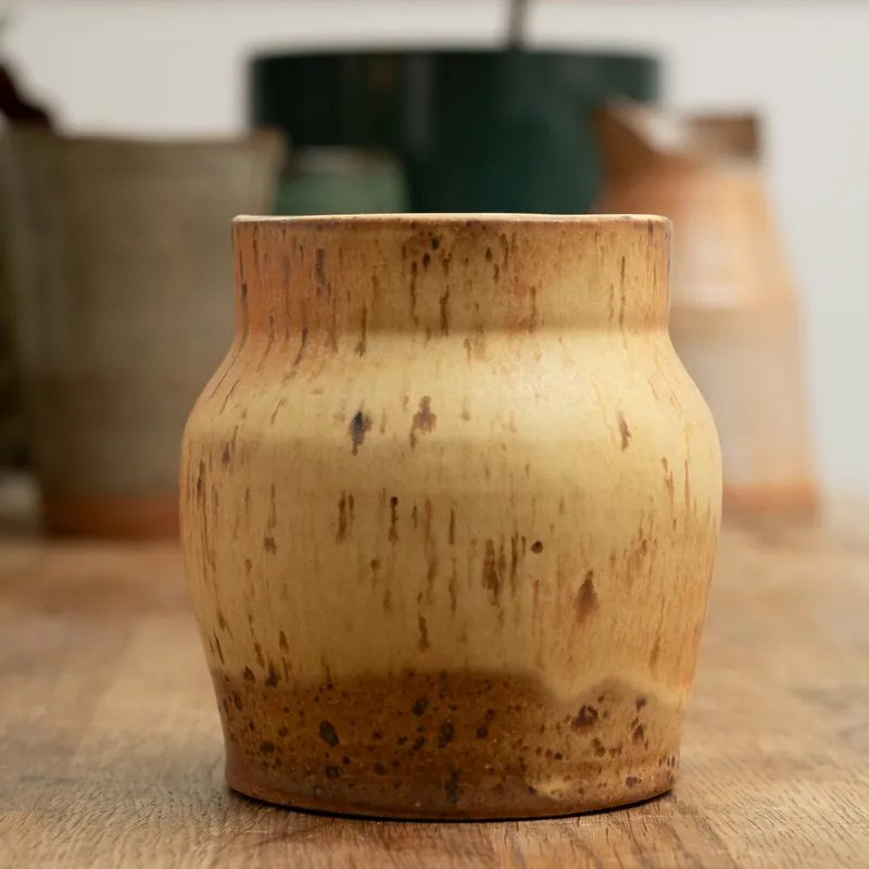 Vase en grès ocre posé sur une table en bois